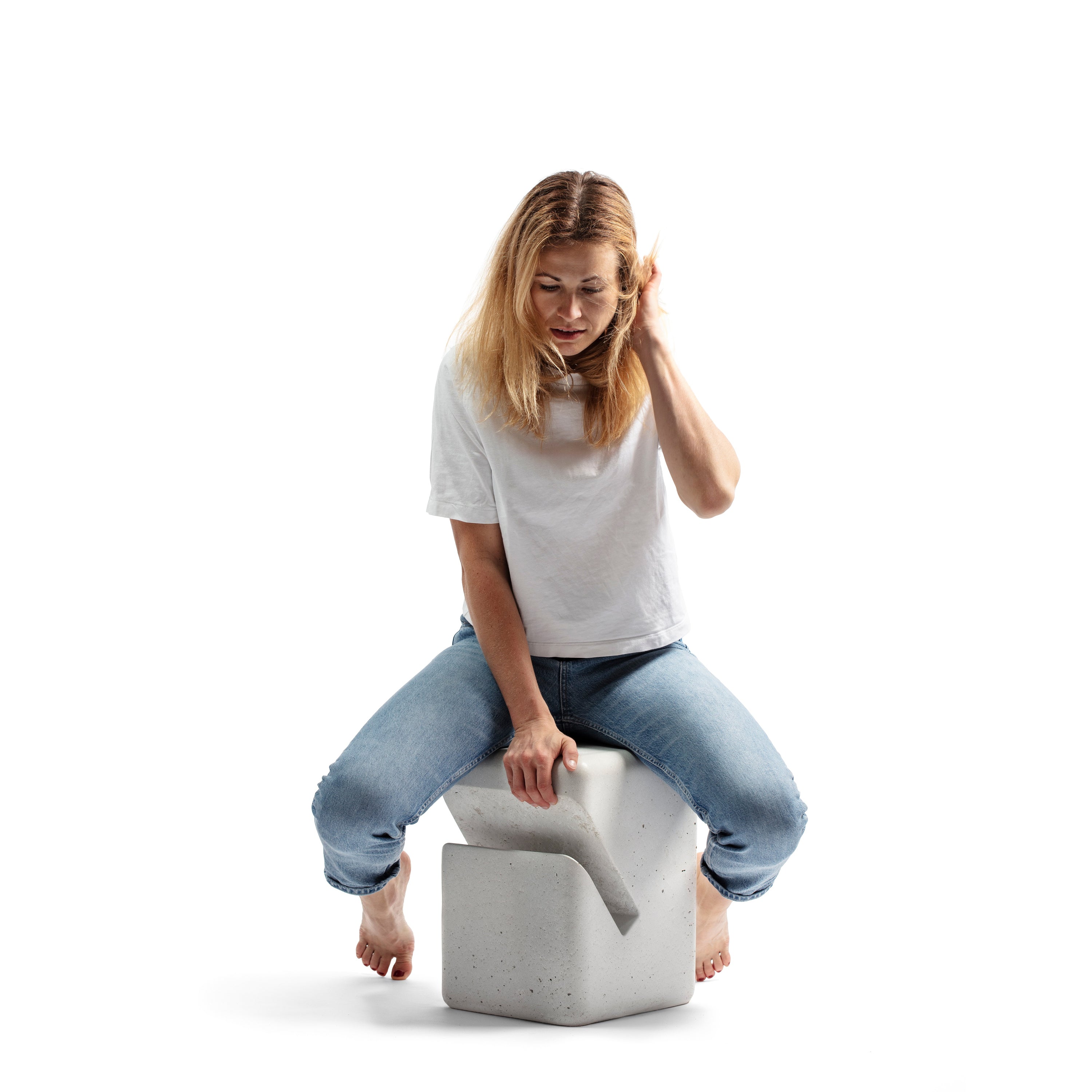 Blond woman siting on a concrete side table in blue jeans and white t-shirt