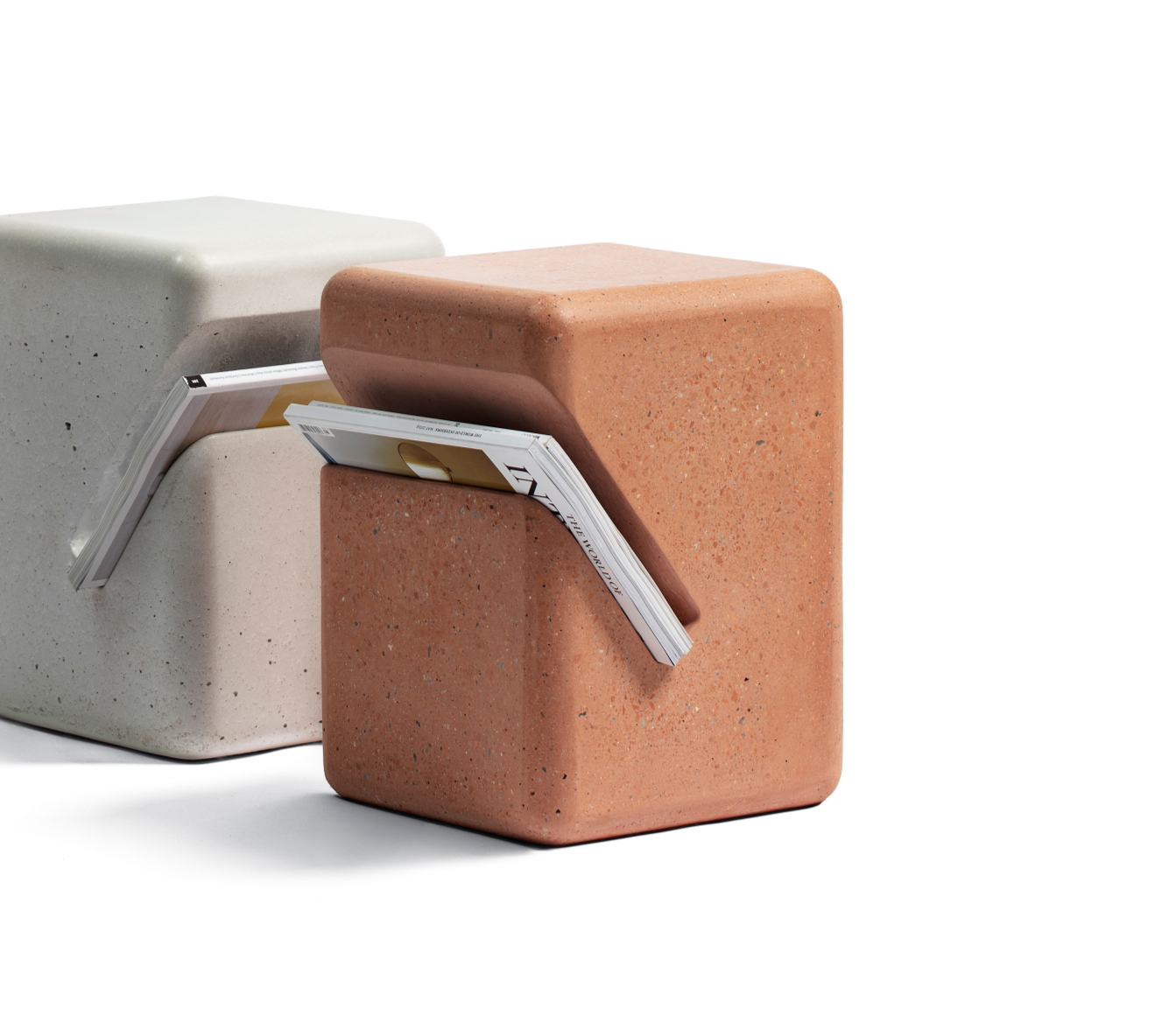 two concrete side tables with diagonal cut for magazines. one brick colour, one white